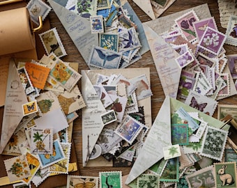 May include: A collection of assorted postage stamps featuring diverse illustrations of flowers, animals, butterflies, and landscapes, organized within several triangular paper envelopes labeled with titles like Autumn Letter.