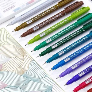 May include: A collection of colorful Exquisite Graphic needle pens. The pens are arranged diagonally, showcasing a range of colors including brown, green, blue, purple, and red. Each pen has a fine tip and the text "EXQUISITE GRAPHIC" printed on the barrel.