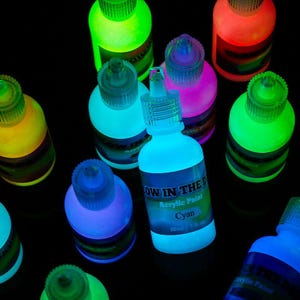 Puede incluir: Una colecci&oacute;n de peque&ntilde;os frascos de pl&aacute;stico exprimibles llenos de pintura acr&iacute;lica que brilla en la oscuridad en varios colores vibrantes. Cada frasco tiene una tapa transparente y una etiqueta de 30 ml. La pintura emite luz de ne&oacute;n.