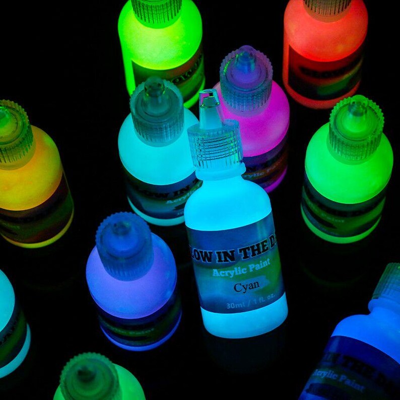Puede incluir: Una colecci&oacute;n de peque&ntilde;os frascos de pl&aacute;stico exprimibles llenos de pintura acr&iacute;lica que brilla en la oscuridad en varios colores vibrantes. Cada frasco tiene una tapa transparente y una etiqueta de 30 ml. La pintura emite luz de ne&oacute;n.