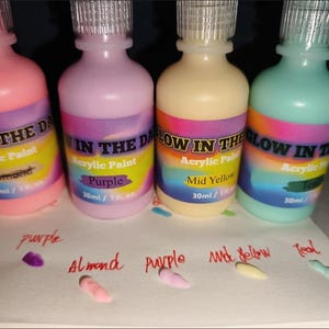 Puede incluir: Cuatro frascos de pl&aacute;stico de pintura acr&iacute;lica que brilla en la oscuridad en rosa, morado, amarillo y verde azulado. Cada frasco tiene una tapa transparente y una etiqueta que dice Glow in the Dark Acrylic Paint con 30 ml de capacidad.