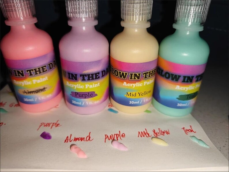 Puede incluir: Cuatro frascos de pl&aacute;stico de pintura acr&iacute;lica que brilla en la oscuridad en rosa, morado, amarillo y verde azulado. Cada frasco tiene una tapa transparente y una etiqueta que dice Glow in the Dark Acrylic Paint con 30 ml de capacidad.