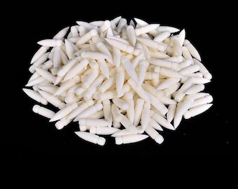 May include: A large pile of small, white, pointed objects with a cylindrical base and a tapered tip. Each individual piece features a smooth, matte finish and a uniform shape, arranged in a dense, unstructured cluster against a black background.