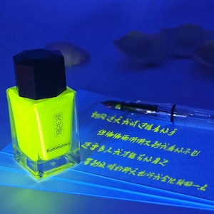 May include: A neon yellow nail polish bottle with a black cap. The bottle has Chinese characters and the word "fluorescence". A clear pen and a blue paper with Chinese text are also in the image.