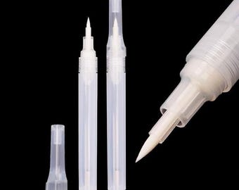 May include: A set of clear plastic refillable pens with fine brush tips. The set includes two pens with translucent caps and one pen shown in a close-up view, highlighting the white synthetic bristles and the hollow barrel design for liquid.