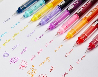 May include: A set of nine Moka gel pens with 0.5 mm tips, featuring barrels in blue, turquoise, yellow, lilac, purple, pink, orange, red, and wine red. Each pen is displayed next to its corresponding ink color swatch and a small planet doodle.