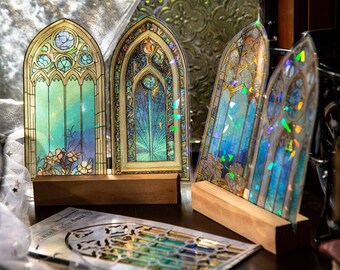 May include: Four arched window-shaped acrylic panels featuring intricate stained glass patterns in shades of blue, green, and gold. The panels display holographic light reflections and are supported by rectangular wooden bases.