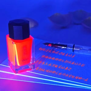 May include: A neon orange nail polish bottle with a black cap, labeled "lava" and "22ml." The bottle sits on a blue surface next to a clear fountain pen and a sheet of paper with red text. The image has a vibrant, glowing effect.