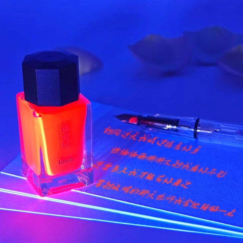 May include: A neon orange nail polish bottle with a black cap, labeled "lava" and "22ml." The bottle sits on a blue surface next to a clear fountain pen and a sheet of paper with red text. The image has a vibrant, glowing effect.