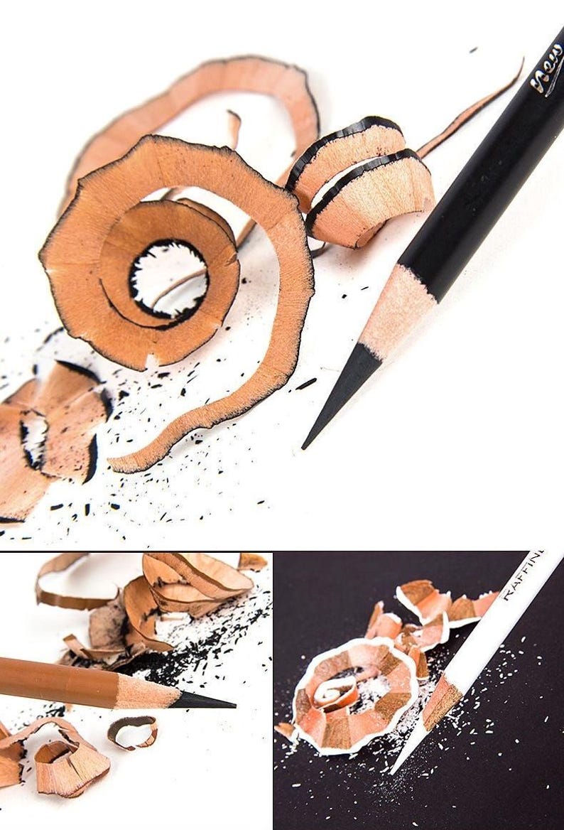 May include: Close-up of three sharpened pencils with wood shavings. The pencils are black, brown, and white. The shavings are curled and scattered around the pencils.
