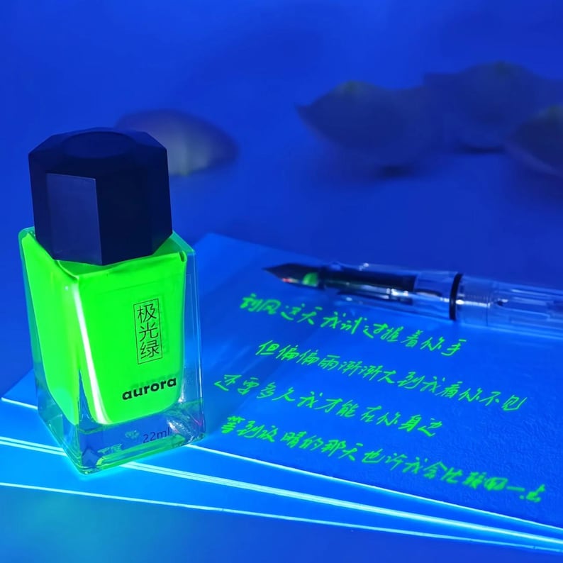 May include: A neon green nail polish bottle with a black cap. The bottle has Chinese text and the word "aurora". A clear pen and handwritten text are in the background.