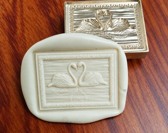 May include: A rectangular metallic stamp featuring an embossed design of two swans facing each other with necks curved to form a heart shape, paired with a matching off-white silicone mold that replicates the same swan imagery.