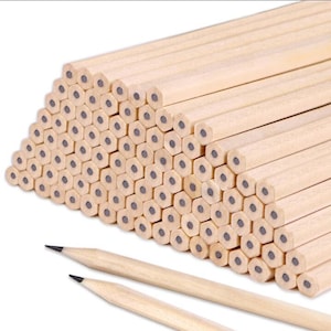 Puede incluir: Una gran pila de lápices de madera con barriles hexagonales y puntas de grafito negro. Dos lápices están sobre la mesa delante de la pila.
