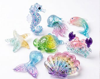 May include: A collection of eight translucent resin sea creature figurines including a seahorse, jellyfish, dolphin, starfish, sea turtle, crab, mermaid tail, and seashell, all featuring colorful gradients and embedded glitter particles.