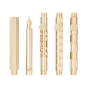 Puede incluir: Una colección de plumas estilográficas y componentes de plumas de color dorado. Las plumas tienen varios diseños, incluyendo patrones geométricos y un diseño de celosía. Una pluma tiene un plumín dorado. Los componentes incluyen un capuchón y cuerpos de pluma.