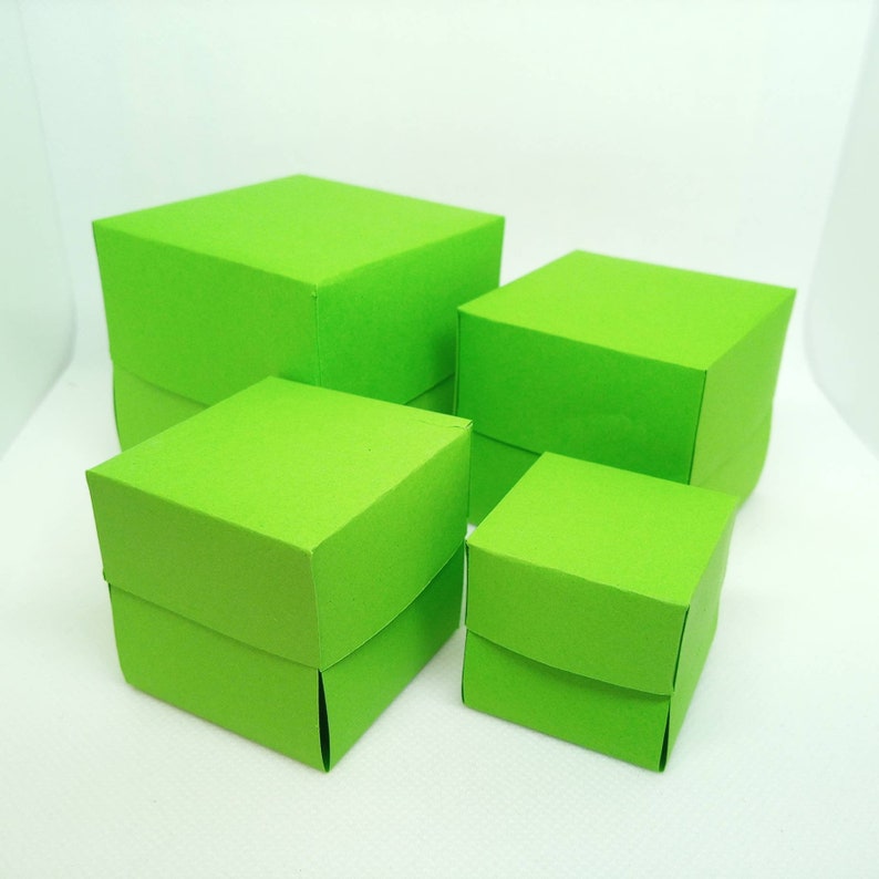 K&ouml;nnte beinhalten: Vier gr&uuml;ne quadratische Boxen in verschiedenen Gr&ouml;&szlig;en, die &uuml;bereinander gestapelt sind. Die Boxen sind aus robustem Karton gefertigt und haben eine glatte, matte Oberfl&auml;che.