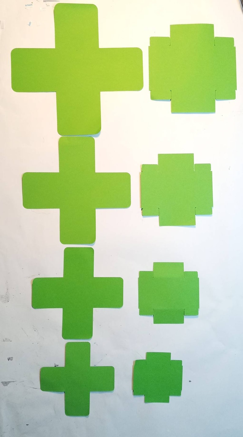 K&ouml;nnte beinhalten: F&uuml;nf gr&uuml;ne Papier-Schablonen zum Basteln von Boxen. Die Schablonen haben die Form eines Pluszeichens mit Laschen an den Seiten. Die Schablonen sind nach Gr&ouml;&szlig;e geordnet, die gr&ouml;&szlig;te oben und die kleinste unten.