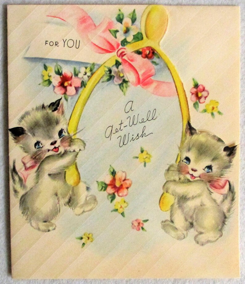May include: A vintage greeting card featuring two fluffy gray kittens holding a large yellow wishbone. The card is decorated with pink ribbons and colorful flowers, with the text FOR YOU and A Get-Well Wish printed in black script on the front.