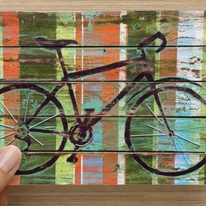 Puede incluir: Una silueta de bicicleta negra sobre un fondo de rayas de colores. El fondo est&aacute; hecho de tablones de madera pintados en tonos de azul, verde, naranja y rojo.