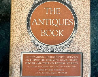 May include: The cover of a book titled "The Antiques Book" with an eagle illustration and the text "Outstanding Authoritative Articles on Furniture, Ceramics, Glass, Silver, Pewter, and Other Collecting Interests. Illustrated with photographs of over two hundred items. Edited by Alice Winchester and the staff of The Magazine Antiques."