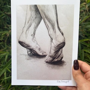 Op de afbeelding: Een houtskooltekening op papier met een paar voeten op de tenen in een gekruiste houding. Het kunstwerk bevat gedetailleerde schaduwen en texturen, met de tekst artbysuzann links zichtbaar en een handtekening in de rechterbenedenhoek.