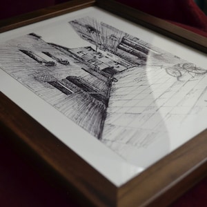 May include: A framed black and white pen and ink drawing of a narrow alleyway with buildings on either side. The drawing is in a dark brown wood frame.