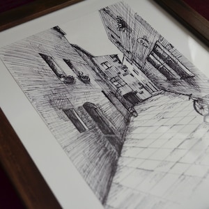 May include: A black and white ink drawing of a narrow street in a European city. The street is lined with tall buildings and there is a bicycle parked on the cobblestone street.