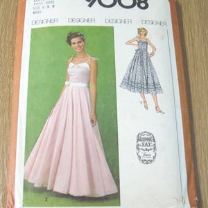 May include: Vintage Simplicity 9008 sewing pattern featuring a pink dress with a white bow and a white belt. The pattern includes two sizes, 6 and 8. The cover also shows a drawing of a blue dress. The pattern is from Gunne Sax.