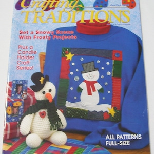 May include: A magazine cover titled "Crafting Traditions" features a blue sweater with a snowman design. The cover also shows a crocheted snowman and the text "Set a Snowy Scene With Frosty Projects."