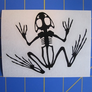 May include: Black silhouette of a frog skeleton on a white background.