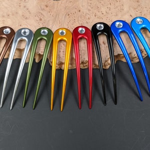 May include: Ten hair pins with a single rhinestone on the top. The pins are in various colors including brown, silver, green, yellow, red, black, and blue.