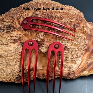 May include: Three red metal hair combs with three tines each. Each comb has a red tiger eye stone at the top.