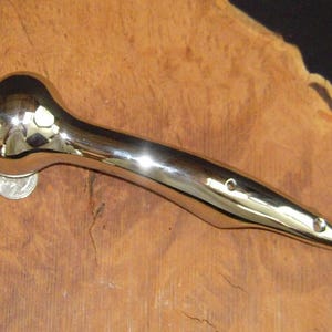 May include: A polished chrome door handle with a rounded end and a long, curved handle.