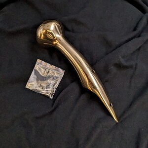 Puede incluir: Un mango de metal de color dorado con un extremo redondeado y una punta puntiaguda. El mango tiene dos agujeros en el lateral. Se incluye una peque&ntilde;a bolsa de tornillos.