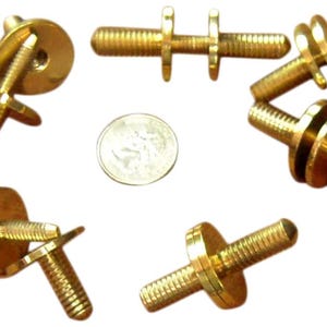 May include: A set of six gold-toned metal furniture feet with threaded screws and round bases. The feet are designed to be attached to the bottom of furniture legs.