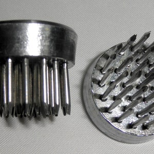 Peut inclure: Deux bases de grenouille florales en argent avec des broches m&eacute;talliques pointues. Les bases sont rondes et ont un bord sur&eacute;lev&eacute;. Les broches sont dispos&eacute;es en cercle.