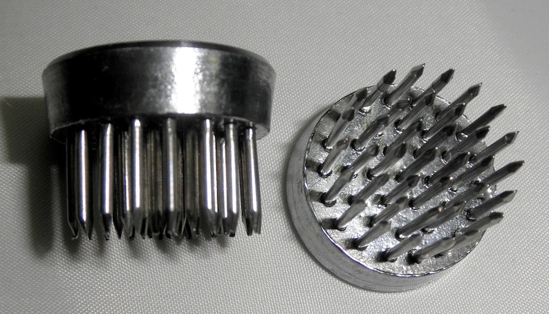 Peut inclure: Deux bases de grenouille florales en argent avec des broches m&eacute;talliques pointues. Les bases sont rondes et ont un bord sur&eacute;lev&eacute;. Les broches sont dispos&eacute;es en cercle.