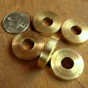 May include: Five brass washers with a hole in the center. The washers are stacked on top of each other.