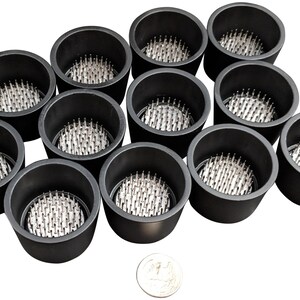 May include: Twelve black floral foam holders with silver pins. The holders are arranged in a circle with a silver coin in the center.