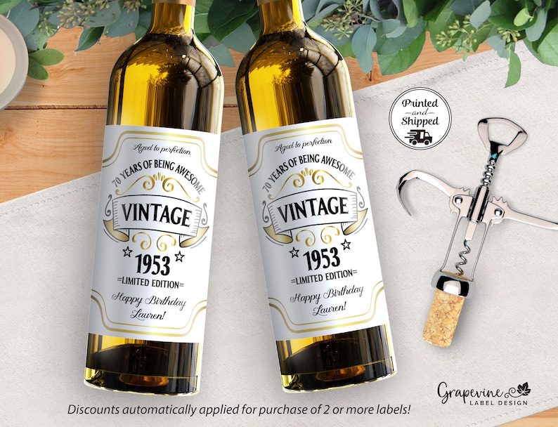 May include: Two white wine bottle labels with gold text. The labels say "Aged to perfection 70 Years of Being Awesome Vintage 1953 Limited Edition Happy Birthday Lauren!"