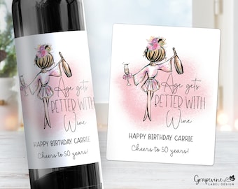 May include: Wine bottle label with a pink and white watercolor background featuring a cartoon illustration of a woman holding a glass of wine. The text on the label reads "Age gets better with wine" and "Happy Birthday Carrie Cheers to 50 years!"