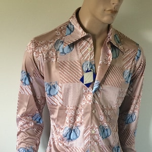 May include: A long-sleeved shirt with a pink background and a geometric pattern of blue pears. The shirt has a button-up front and a collar.