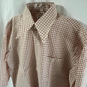 Peut inclure: Une chemise à manches longues à boutons en gingham brun et blanc avec un col pointu. La chemise a une seule poche poitrine.