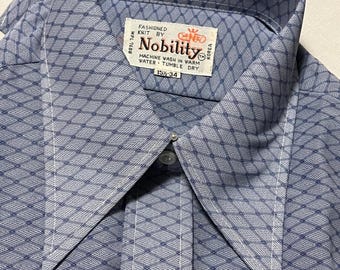 May include: A blue and white patterned shirt with a pointed collar. The shirt is labeled "Nobility" and has a size tag that reads "15 1/2 - 34".
