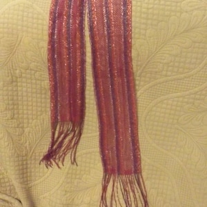 May include: A long, pink and purple striped scarf with fringe on the ends.