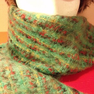 May include: A green, red, and yellow fuzzy scarf with a textured pattern.