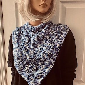 May include: A blue and white knitted scarf with a lacy pattern. The scarf is worn by a mannequin with a blonde wig.