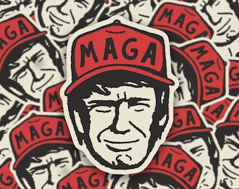 May include: A red and black sticker with a cartoon image of a person wearing a red hat with the text "MAGA" on it. The person has black hair and a white face with a smile.