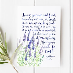 May include: A white card with a watercolor illustration of lavender and text in blue script. The text reads, "Love is patient and kind..." and is from 1 Corinthians 13:4-6. The card has a floral theme.