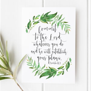 May include: A white print with the text "Commit to the Lord whatever you do and he will establish your plans. Proverbs 16:3" in black script. The text is surrounded by a watercolor wreath of green leaves.